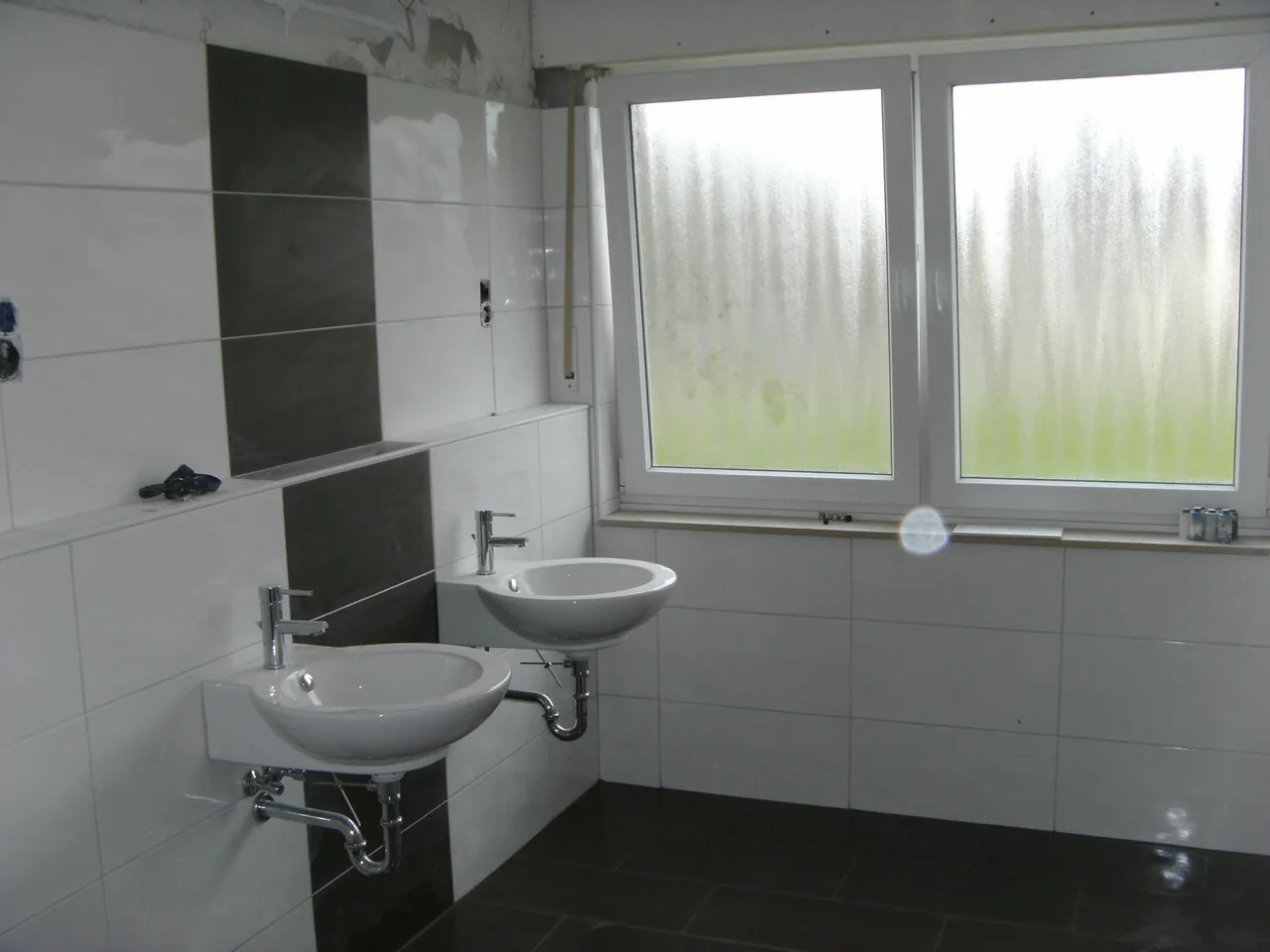 Bad mit Wandfliesen und zwei Waschbecken